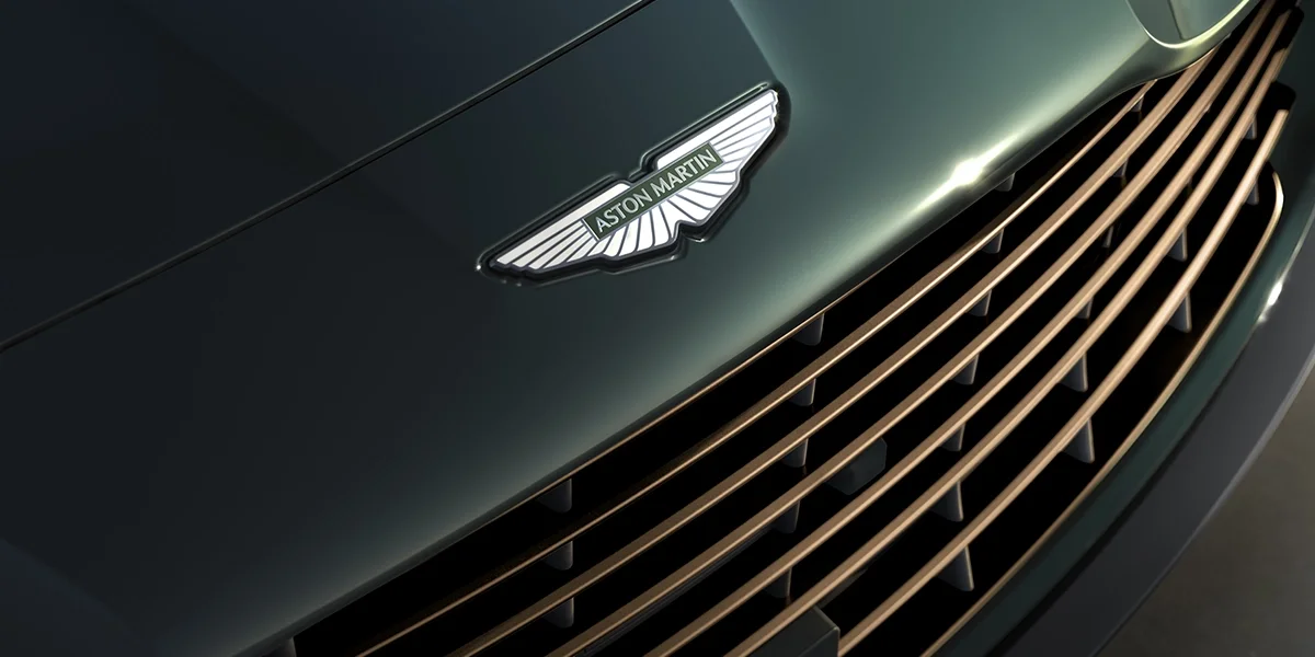 Aston Martin Vanquish Volante convertible interior with open roof, digital infotainment system, and tan leather craftsmanship under natural light.