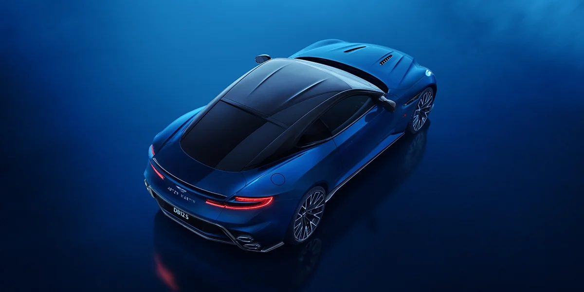 Rear detail of the Aston Martin DB12 S featuring a carbon fiber spoiler, slim LED taillights, and the Aston Martin badge over the trunk lid.