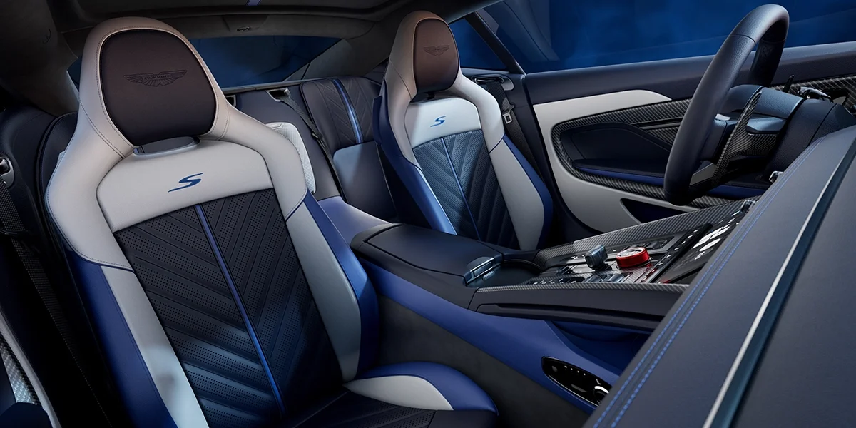 Rear view of the Aston Martin DB12 S showing its quad exhaust outlets, illuminated taillight strip, and DB12 S badging under soft blue lighting.