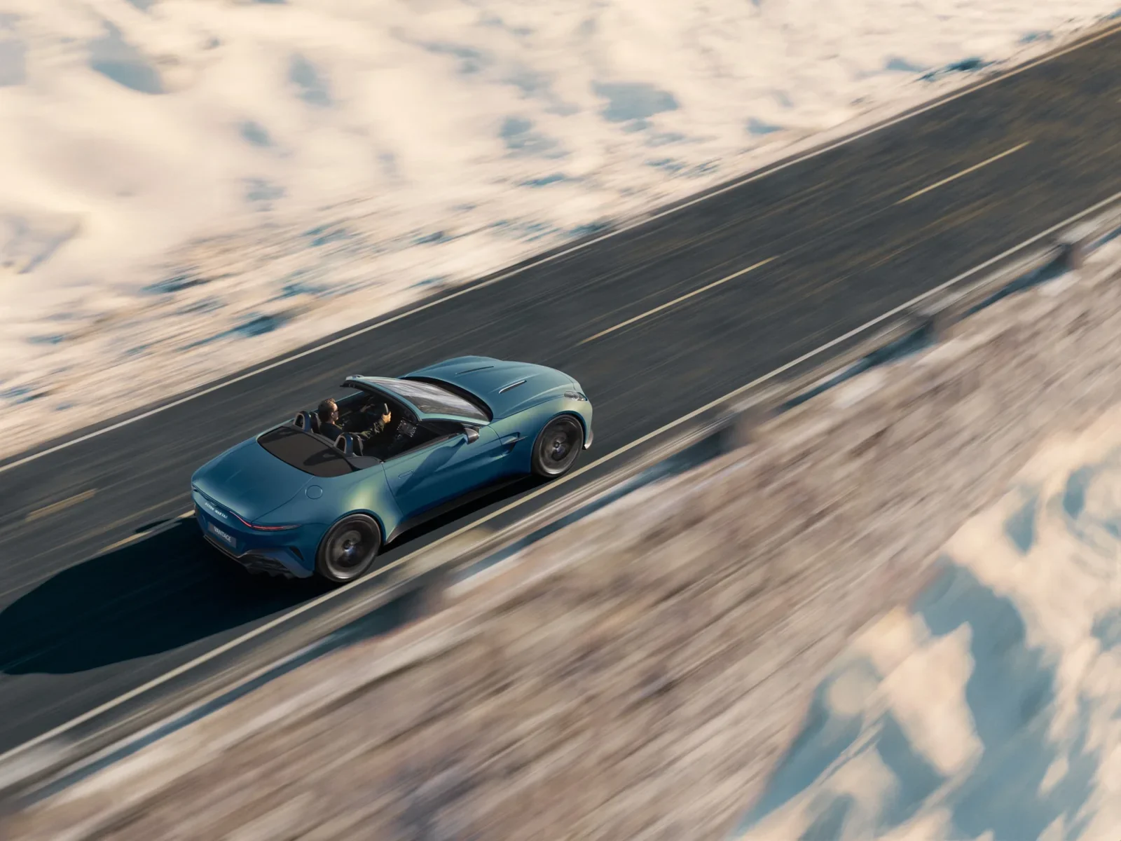 Aston Martin Vantage Roadster driving on a snowy mountain road