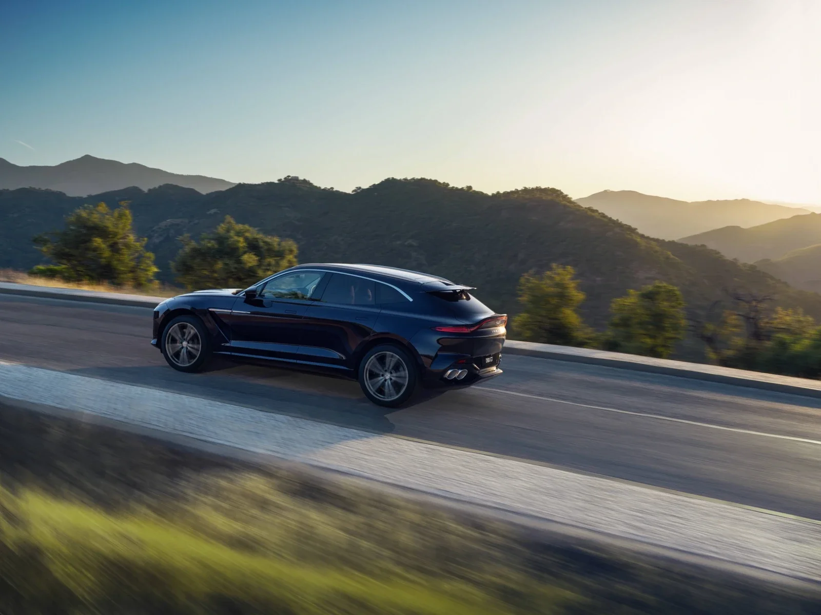 Aston Martin DBX GT rear three-quarter view driving on the road near Aston Martin Rancho Mirage